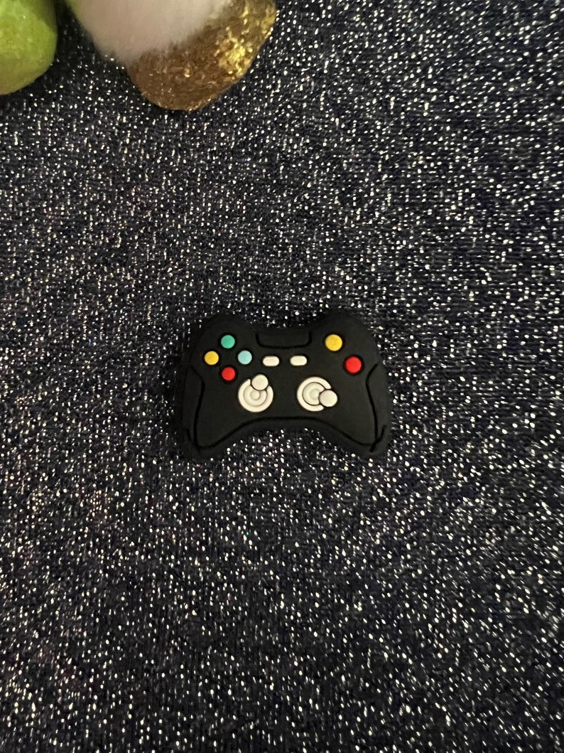 May include: Black rubber game controller charm with colorful buttons.