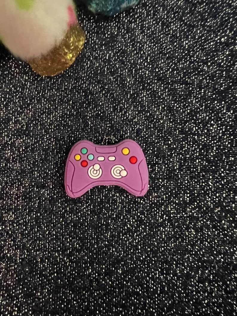 May include: Purple video game controller charm with colorful buttons.