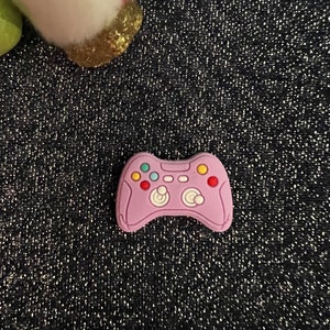 May include: A pink plastic video game controller charm with colorful buttons.