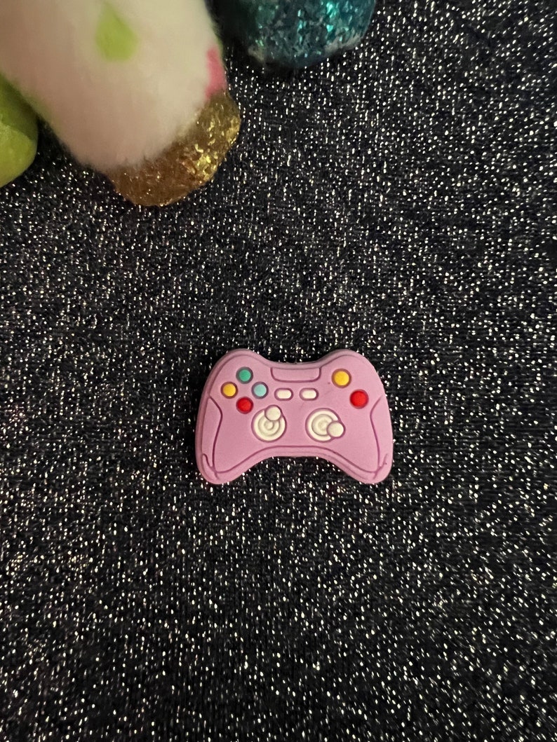 May include: A pink plastic video game controller charm with colorful buttons.