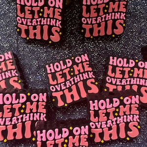 May include: Multiple black and pink square-shaped pins with the text "Hold on let me overthink this" in a retro font.