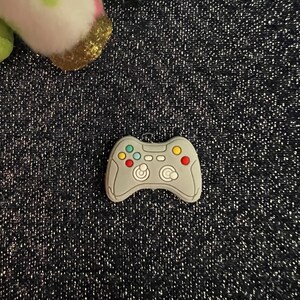 May include: A gray plastic video game controller charm with colorful buttons.