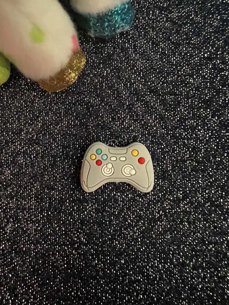 May include: A gray plastic video game controller charm with colorful buttons.