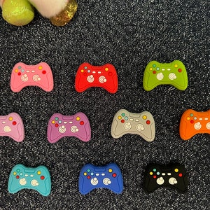 May include: Ten colorful plastic game controller charms in various colors including pink, red, green, blue, orange, gray, and black.