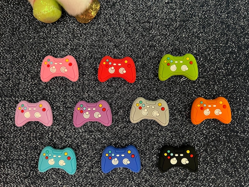 May include: Ten colorful plastic game controller charms in various colors including pink, red, green, blue, orange, gray, and black.