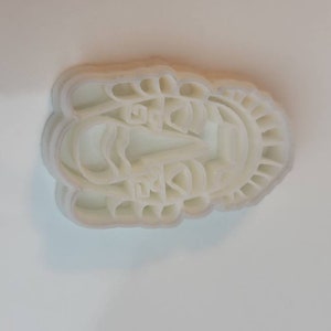 May include: A white plastic cookie cutter in the shape of a boat with Chinese characters. The cutter has a scalloped edge and is designed to create detailed cookies or pastries. The boat design includes a sail and other intricate details.