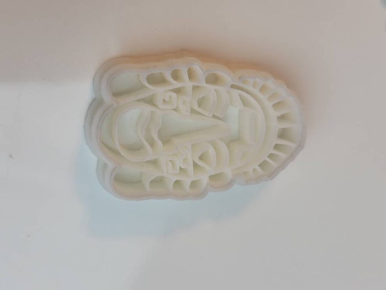 May include: A white plastic cookie cutter in the shape of a boat with Chinese characters. The cutter has a scalloped edge and is designed to create detailed cookies or pastries. The boat design includes a sail and other intricate details.