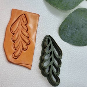以下が含まれることがあります： 葉の形をしたクッキーカッター2個セット。大きなカッターは茶色の革製、小さなカッターは緑色のプラスチック製です。