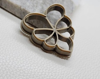 Könnte beinhalten: Ein goldfarbener Metall-Ausstecher in Form einer Blume mit fünf Blütenblättern.