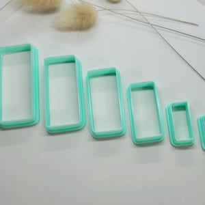 May include: Set of six turquoise plastic rectangle cookie cutters of varying sizes.