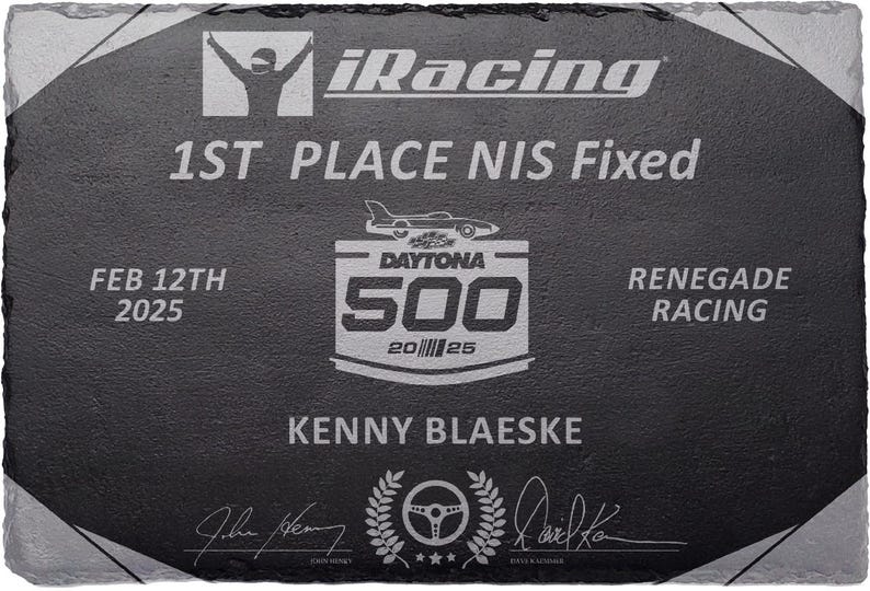 Puede incluir: Placa de pizarra negra con texto y gr&aacute;ficos blancos grabados. La placa conmemora un evento de carreras, con el texto "1ST PLACE NIS Fixed", "DAYTONA 500" y el nombre "KENNY BLAESKE". Tambi&eacute;n se incluye la fecha "FEB 12TH 2025".