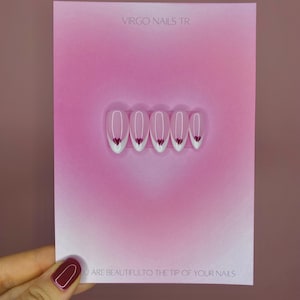 Könnte beinhalten: Eine rosa Karte mit dem Text "VIRGO NAILS TR" oben. Die Karte zeigt sechs weiße und rosa Press-On-Nägel mit einem Herzdesign. Der Text "YOU ARE BEAUTIFUL TO THE TIP OF YOUR NAILS" steht unten.