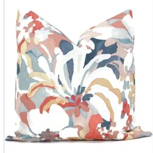 May include: A white pillow with a floral pattern in shades of red, orange, blue, and gray. The pillow has a soft, textured fabric.