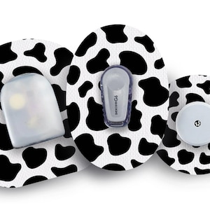 Può includere: Tre cerotti rotondi bianchi con un design a stampa di mucca nera. I cerotti hanno forme diverse attaccate a loro, tra cui un contenitore di plastica trasparente, un piccolo dispositivo grigio con il testo "dexcom G4" su di esso e un pulsante rotondo bianco.