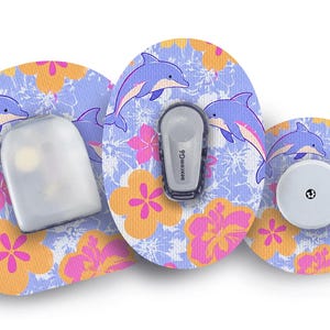 May include: Three adhesive patches with a light blue background featuring a pattern of purple dolphins and orange and pink hibiscus flowers. The patches are shaped to fit around medical devices, including one labelled with the text Dexcom G6.