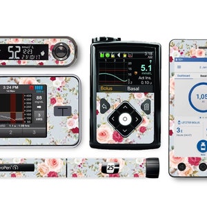 以下が含まれることがあります： 糖尿病管理システム用の花柄のスキンの4点セット。セットには、連続血糖値モニター用スキン、インスリンポンプ用スキン、ペン用スキン、スマートフォン用スキンの4種類が含まれています。スキンは、薄い青色の背景にピンクと赤のバラが描かれています。