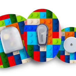 Puede incluir: Tres pegatinas redondas de colores con un patrón de bloques de Lego. Las pegatinas presentan una variedad de colores, incluyendo rojo, azul, verde, amarillo y blanco. Las pegatinas están diseñadas para ser usadas en dispositivos médicos.