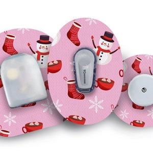 May include: Three round pink and white patterned adhesive patches with a snowman and hot chocolate design. One patch has a clear plastic cover, one has a white round sensor, and one has a white sensor with a Dexcom G6 logo.