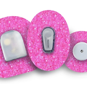 Könnte beinhalten: Drei runde, rosa Klebeflecken mit Glitzer. Der mittlere Fleck hat einen kleinen weißen Sensor mit einem schwarzen Punkt. Der linke Fleck hat einen durchsichtigen Sensor mit einem weißen Licht. Der rechte Fleck hat einen grauen Sensor mit dem Text "dexcom G6".