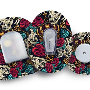 Op de afbeelding: Drie ronde afdekkingen voor medische apparaten met een schedel-, rozen- en kroonmotief. Het motief is in tinten rood, goud, zwart en blauw. De afdekkingen zijn ontworpen om over een medisch apparaat te passen.