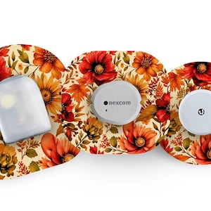 May include: Three adhesive patches with a vibrant autumn floral pattern featuring red poppies, orange sunflowers, and brown leaves. The patches are applied to three different medical devices, including one with the text Dexcom visible.