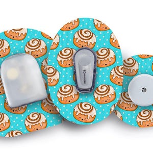Puede incluir: Accesorios para dispositivos médicos con un divertido diseño de rollo de canela sobre un fondo turquesa. Incluye un sensor y un transmisor, diseñados para el sistema de monitorización continua de glucosa Dexcom G6.
