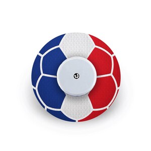 Può includere: Un cerotto adesivo circolare con un motivo a pallone da calcio con pannelli blu, bianchi e rossi. Un piccolo sensore medico circolare bianco, con una minuscola icona nera al centro, è posizionato direttamente sopra il cerotto decorato.