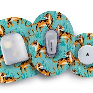 以下が含まれることがあります： ターコイズブルーの背景に、オレンジと黒の虎が繰り返し描かれた、丸い粘着パッチが3つあります。これらのパッチは、医療機器を覆うように設計されています。最も大きなパッチには、白い医療機器が取り付けられています。機器には「dexcom G6」という文字が書かれています。