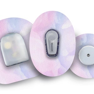 May include: Three round, white adhesive patches with a pink and blue watercolour design. The patches have different sized, round, white objects attached to them. The centre patch has a small, round, white object with a black dot in the centre. The left patch has a larger, oval, white object with a clear, plastic cover. The right patch has a small, rectangular, white object with the text "dexcom G6" printed on it.