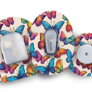 May include: Three round adhesive patches with a colorful butterfly pattern. The patches are designed for medical devices and feature a clear plastic reservoir, a white button, and a blue and white insulin pump.