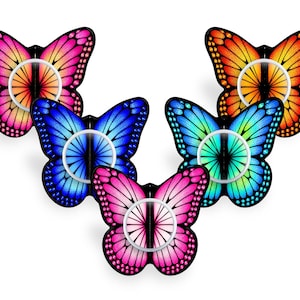 Op de afbeelding: Een verzameling van vijf vlindervormige telefoonhouders, elk met een levendig kleurverloop in roze, oranje, blauw en turquoise. Elke houder heeft een centrale witte ringbevestiging en zwarte vleugelomlijningen met gedetailleerde patronen.