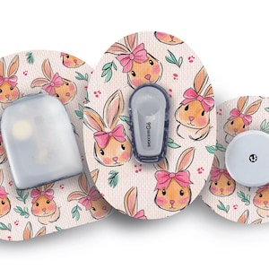 Può includere: Set di accessori per dispositivi medici con un motivo ripetuto di coniglietti dei cartoni animati con fiocchi rosa e foglie verdi. Il set include un sensore, un trasmettitore e un ricevitore, tutti decorati.