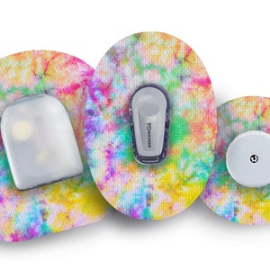 Puede incluir: Tres parches médicos redondos con un patrón de tie-dye. Los parches son en tonos de rosa, amarillo, azul y verde. El parche central tiene un pequeño disco blanco con un punto negro en el centro. El parche izquierdo tiene una cubierta de plástico transparente. El parche derecho tiene un pequeño dispositivo gris con el texto "dexcom G6" impreso en él.
