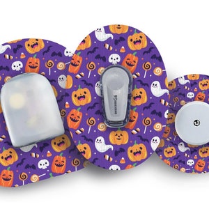 Könnte beinhalten: Ein Zubehörset für medizinische Geräte zum Thema Halloween. Das Set enthält einen Sensor, einen Sender und einen Empfänger, die alle mit einem lila Hintergrund und einem Muster aus orangefarbenen Kürbissen, Geistern, Fledermäusen und Süßigkeiten verziert sind. Die Geräte sind für den medizinischen Gebrauch bestimmt.