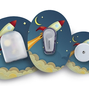 Puede incluir: Tres diseños diferentes para un parche de dispositivo médico. Cada parche presenta un cohete de dibujos animados volando por un cielo nocturno con estrellas y una luna creciente. El texto "dexcom G6" es visible en uno de los parches.