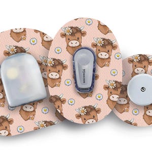 Könnte beinhalten: Eine Sammlung von Zubehör für medizinische Geräte, darunter ein Sensor und ein Sender, mit einem sich wiederholenden Muster von Cartoon-Hochlandrindern mit Gänseblümchenkränzen auf hellrosa Hintergrund.