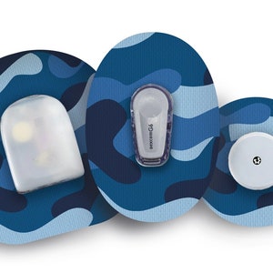 Könnte beinhalten: Drei blaue und weiße Tarnmuster-Klebepatches mit verschiedenen medizinischen Geräten. Die Geräte sind weiß und transparent mit einem kleinen schwarzen Punkt auf einem davon. Der Text "dexcom G6" ist auf einem der Geräte sichtbar.