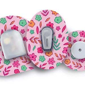 Könnte beinhalten: Medizinische Geräte mit floralem Muster. Das Set enthält einen Sensor, einen Sender und einen runden Patch. Der rosa Hintergrund ist mit Blumen in Rosa, Orange und Grün verziert.