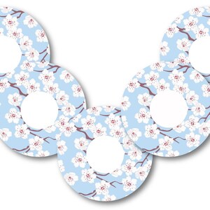 Op de afbeelding: Vijf ronde stickers met een lichtblauwe achtergrond en een wit bloemenpatroon. De bloemen zijn wit met een roze centrum. De stickers hebben een witte cirkel in het midden.