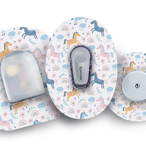 Puede incluir: Tres parches médicos redondos con fondo blanco y un patrón repetido de unicornios, arcoíris y nubes de colores. Los parches están diseñados para un monitor de glucosa continuo.