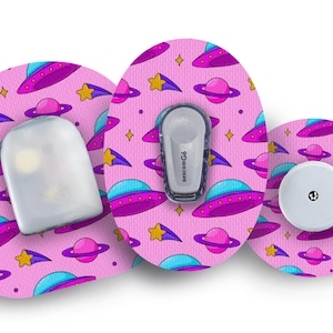 May include: Three pink, round, adhesive patches with a repeating pattern of flying saucers, planets, and shooting stars. The patches are designed for a medical device and have a clear plastic cover.