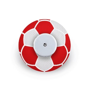 May include: A circular adhesive patch featuring a red and white football pattern with a hexagonal design. The centre of the patch has a smooth, white, circular plastic sensor device with a small black icon printed in the middle of the surface.