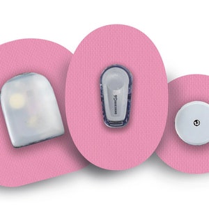 Può includere: Tre cerotti adesivi rotondi rosa con sensori rotondi bianchi di diverse dimensioni. Il sensore centrale ha la scritta "Dexcom G6" stampata.