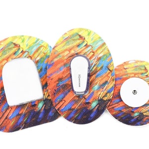 May include: Three colorful adhesive patches with a white sensor in the center of one patch. The patches have a colorful abstract design with orange, yellow, blue, and green colors.
