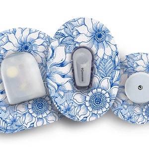 Könnte beinhalten: Drei runde Klebepflaster mit einem blauen und weißen Blumenmuster. Die Pflaster sind für ein medizinisches Gerät und tragen den Text "dexcom G6".