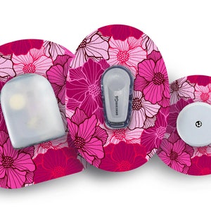 May include: Medical device accessories with a floral pattern in shades of pink and fuchsia. The image shows three components: a sensor, a transmitter labeled "dexcom G6", and a white disc. The floral design covers the adhesive patches.