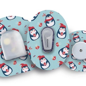 Könnte beinhalten: Drei runde, blau-weiße medizinische Aufkleber mit Pinguin-Motiv. Die Aufkleber zeigen einen rot-weißen Pinguin mit Weihnachtsmütze, der einen Zuckerstock hält. Die Aufkleber sind für ein medizinisches Gerät bestimmt und einer der Aufkleber trägt den Text "dexcom G6".