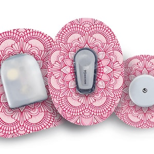 Könnte beinhalten: Drei medizinische Gerätekomponenten mit einem rosa Mandala-Muster. Die Komponenten umfassen einen Sensor, einen Sender mit der Aufschrift "Dexcom G6" und ein rundes Gerät. Die Geräte sind weiß und grau.