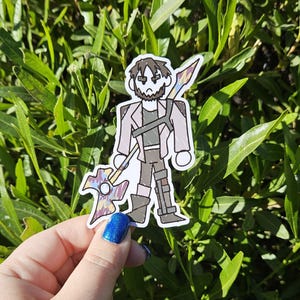 May include: A sticker of a cartoon character holding a colorful spear. The character is wearing a brown jacket, a black shirt, and brown pants. The character has brown hair and a beard. The character has a serious expression on their face.