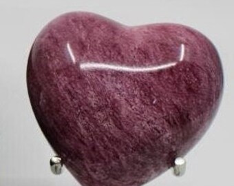 Pode incluir: Uma urna em forma de coração feita de mármore rosa com um suporte de metal prateado. A urna é uma peça decorativa para guardar cinzas.